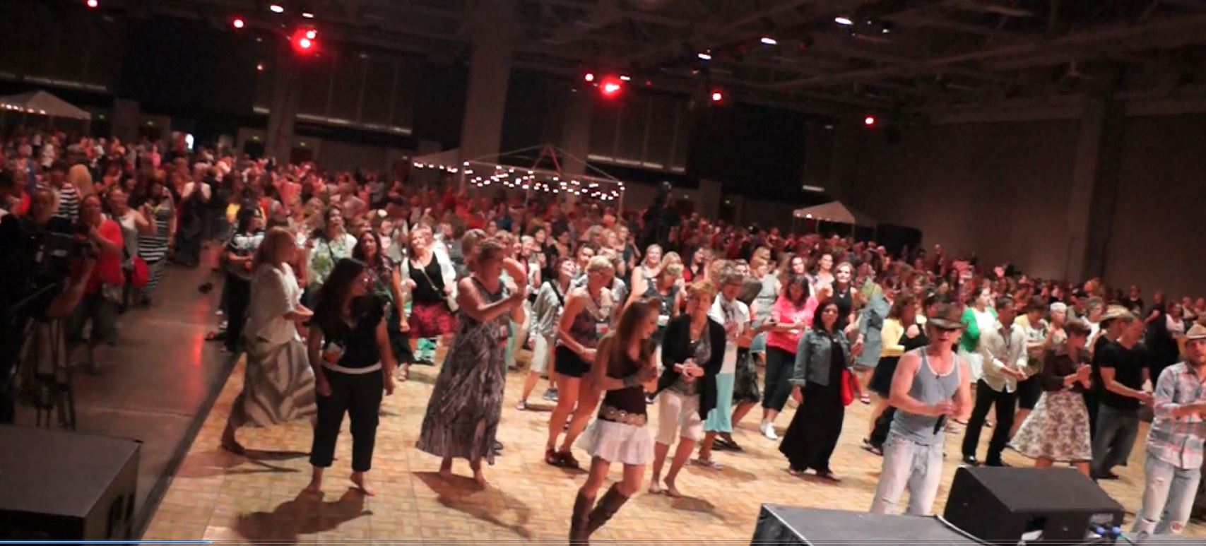 A crowd of people standing in front of stage lights.