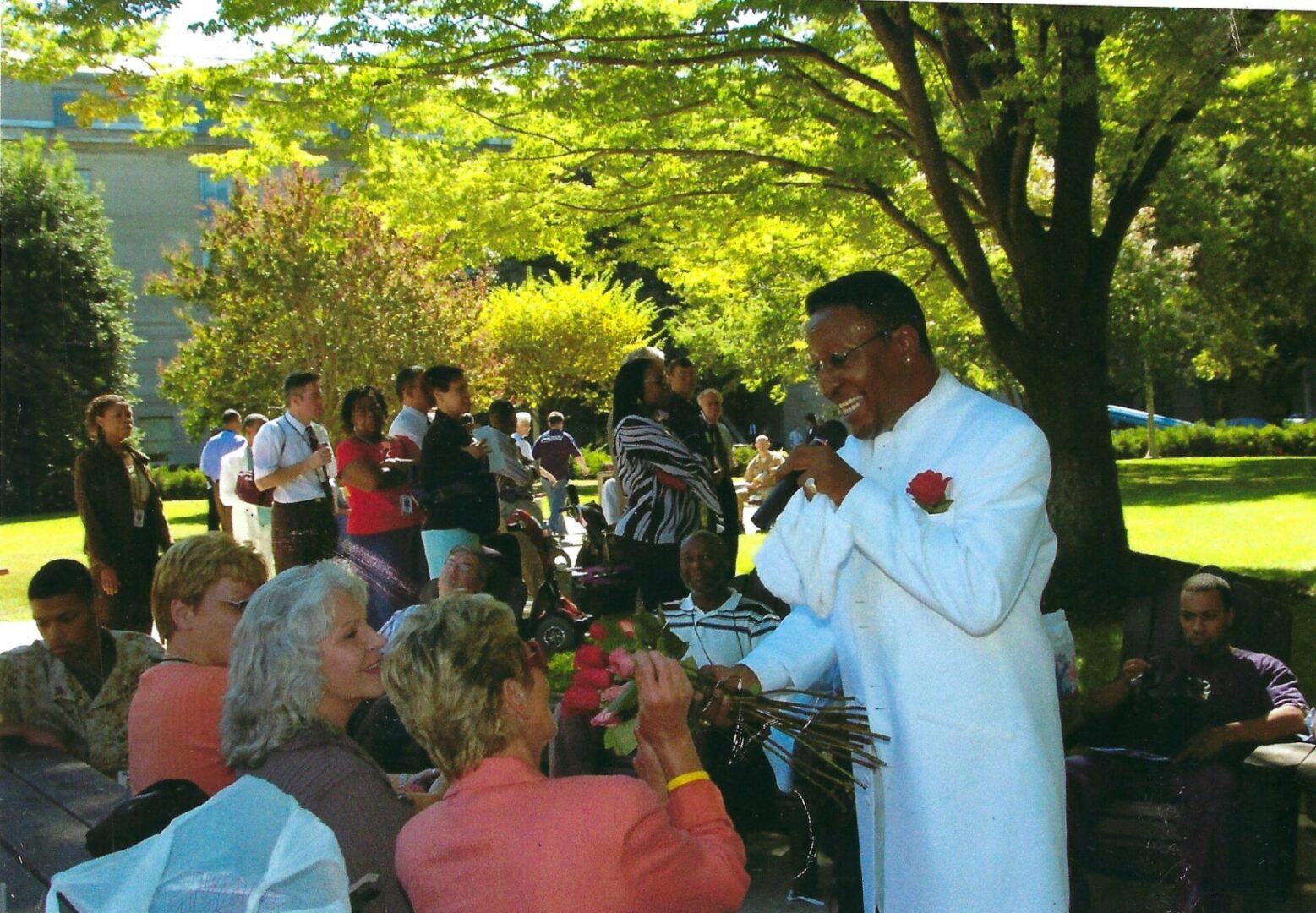 A man in white is singing to the crowd.