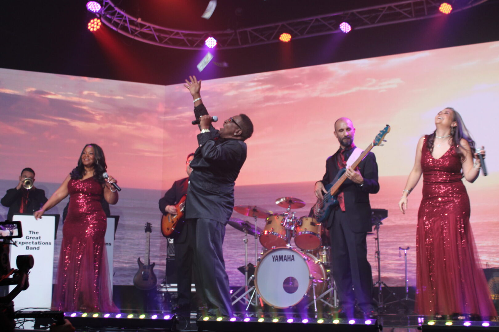 A band performing on stage with the ocean in the background.